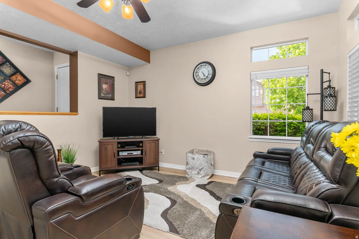 Living room featuring light wood-type flooring, a ceiling fan, and a textured ceiling