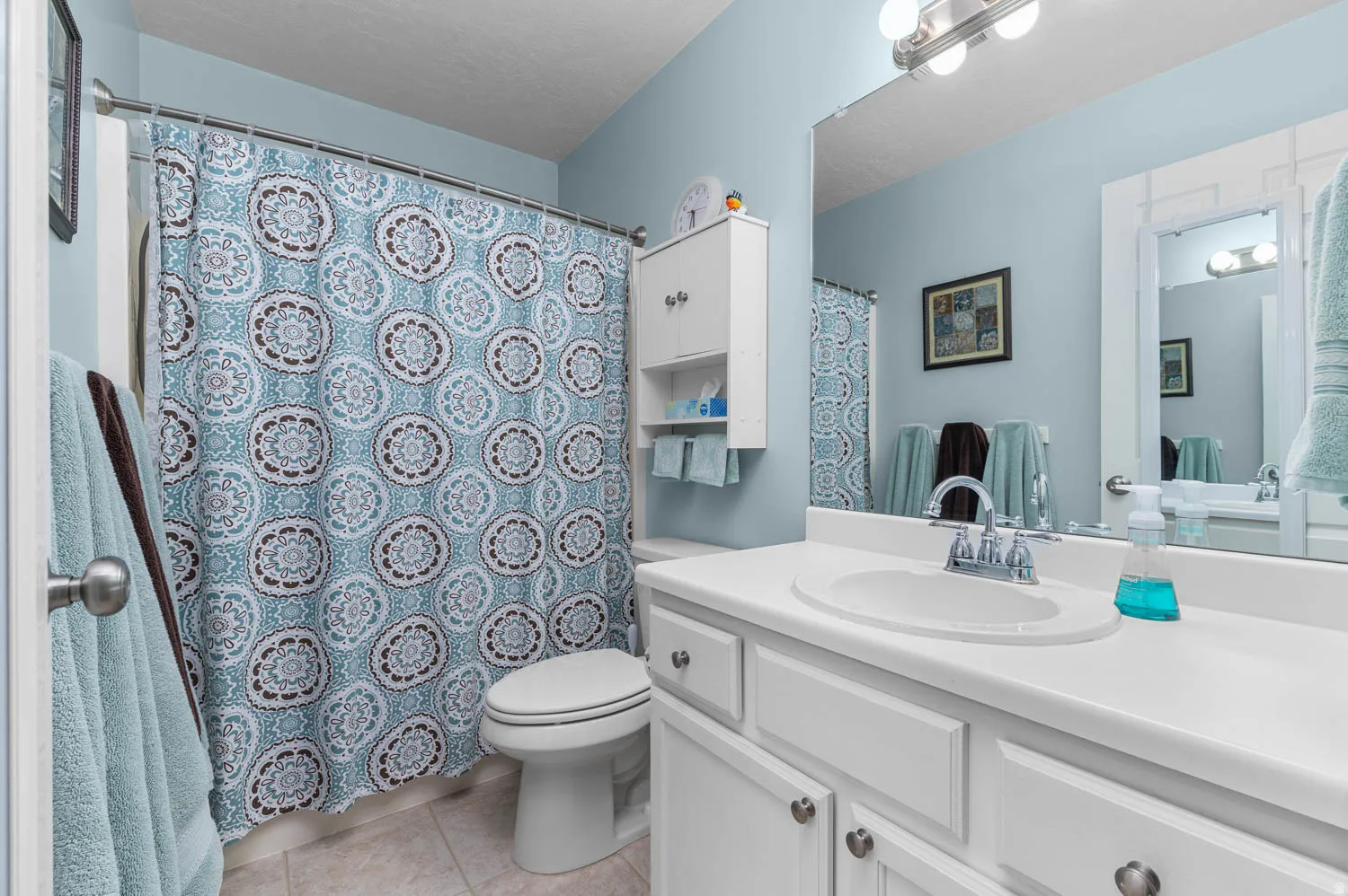 Bathroom with vanity, a shower with shower curtain, and light tile patterned floors
