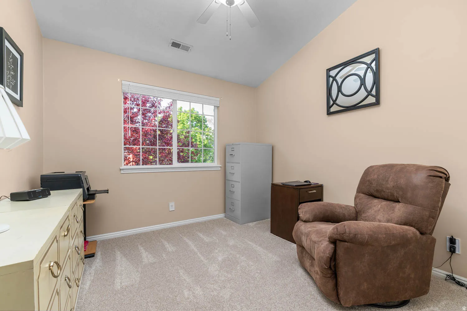 Living area with light colored carpet, vaulted ceiling, and a ceiling fan