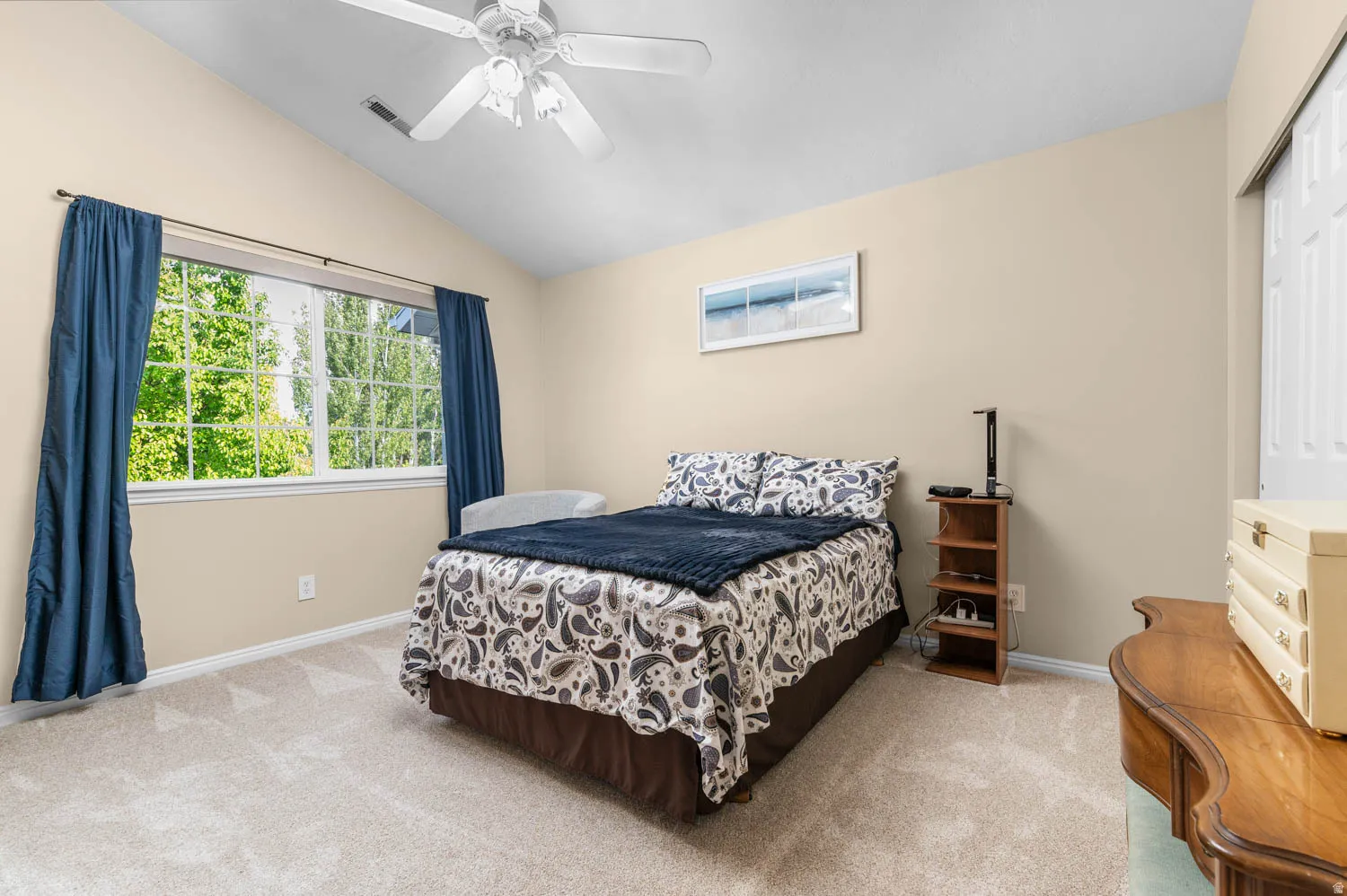 Bedroom with vaulted ceiling, light colored carpet, and ceiling fan