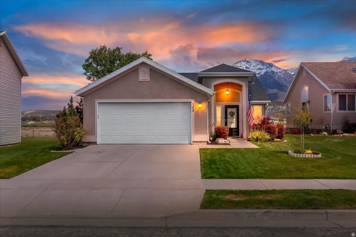 Ranch-style home with stucco siding, an attached garage, a front yard, and driveway