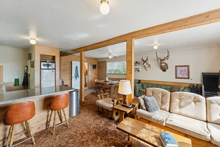 Living area with dark colored carpet, wood walls, a textured ceiling, a ceiling fan, and wallpapered walls