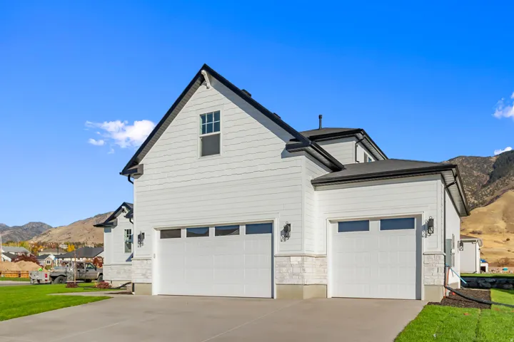 View of property exterior with a mountain view, concrete driveway, and stone siding
