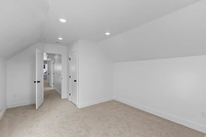 Additional living space with lofted ceiling, light colored carpet, and recessed lighting