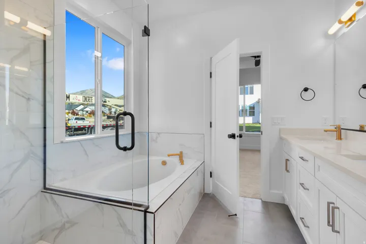 Bathroom with a garden tub, double vanity, light tile patterned flooring, and a marble finish shower