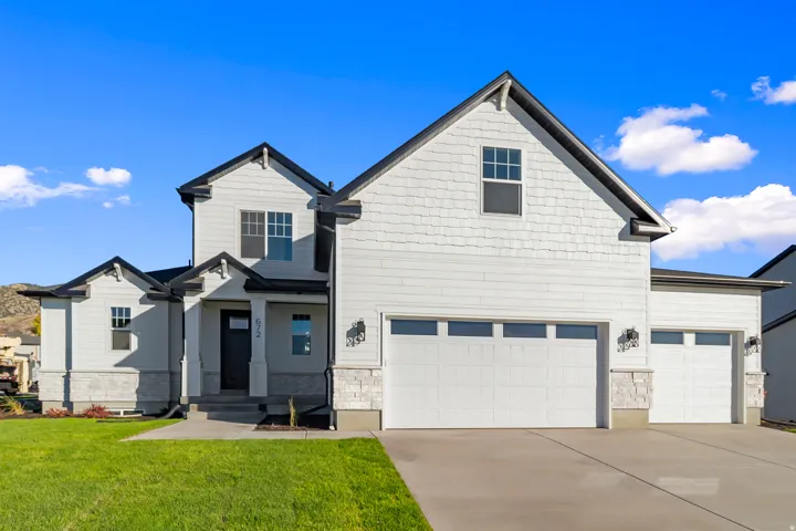 Craftsman house featuring concrete driveway, stone siding, a front lawn, and an attached garage