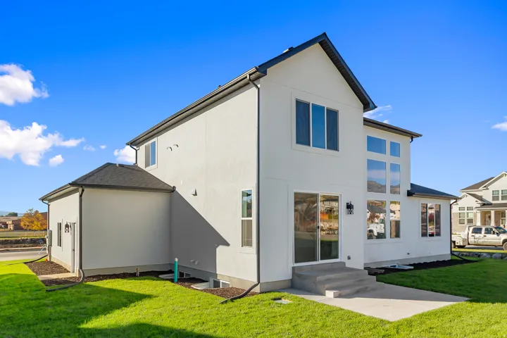 Back of house with a lawn, stucco siding, and entry steps