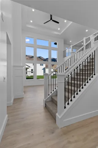 Stairway featuring a ceiling fan, wood finished floors, a raised ceiling, recessed lighting, and a mountain view