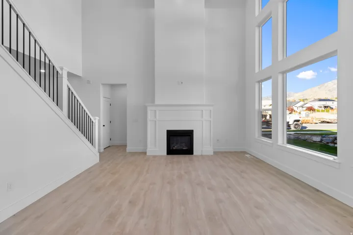 Unfurnished living room with light wood-style flooring, a mountain view, a high ceiling, and a fireplace