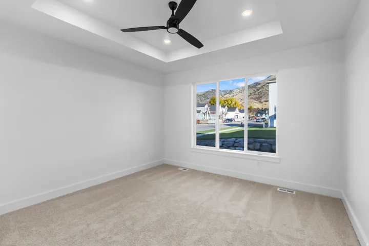 Spare room with a raised ceiling, light carpet, recessed lighting, ceiling fan, and a mountain view