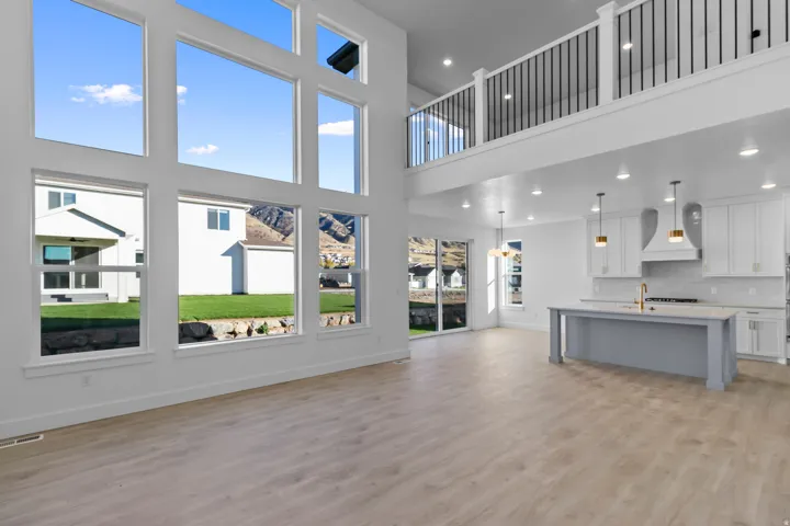 Unfurnished living room with a high ceiling, light wood-style flooring, and recessed lighting