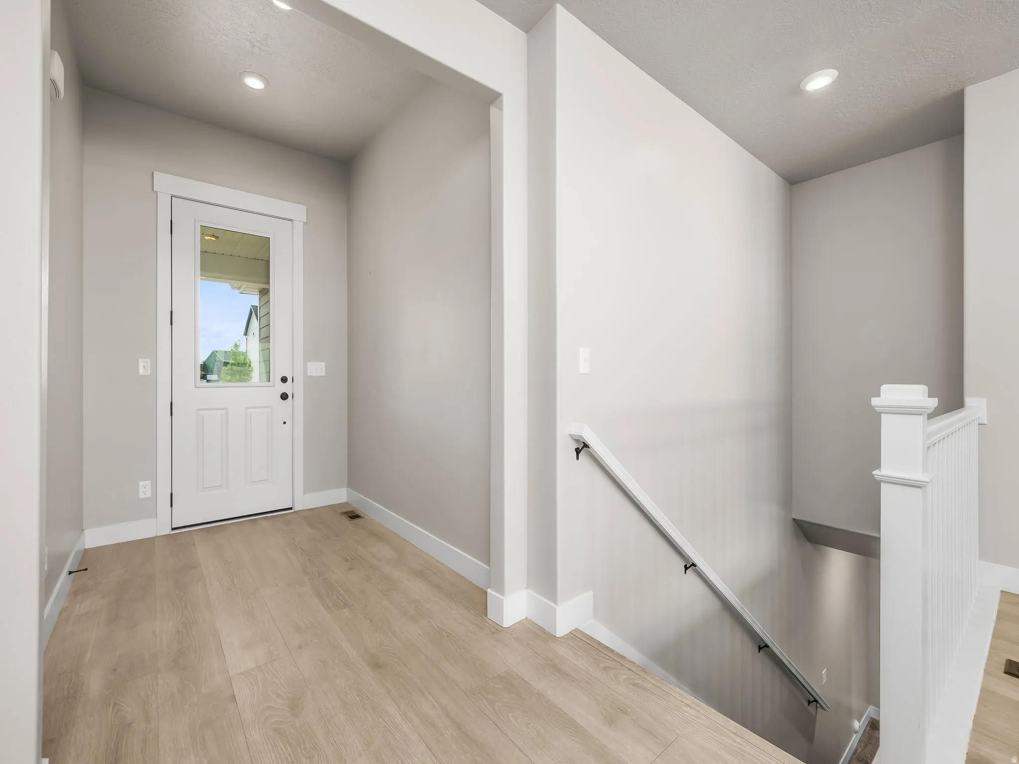 Entryway with light wood finished floors and recessed lighting