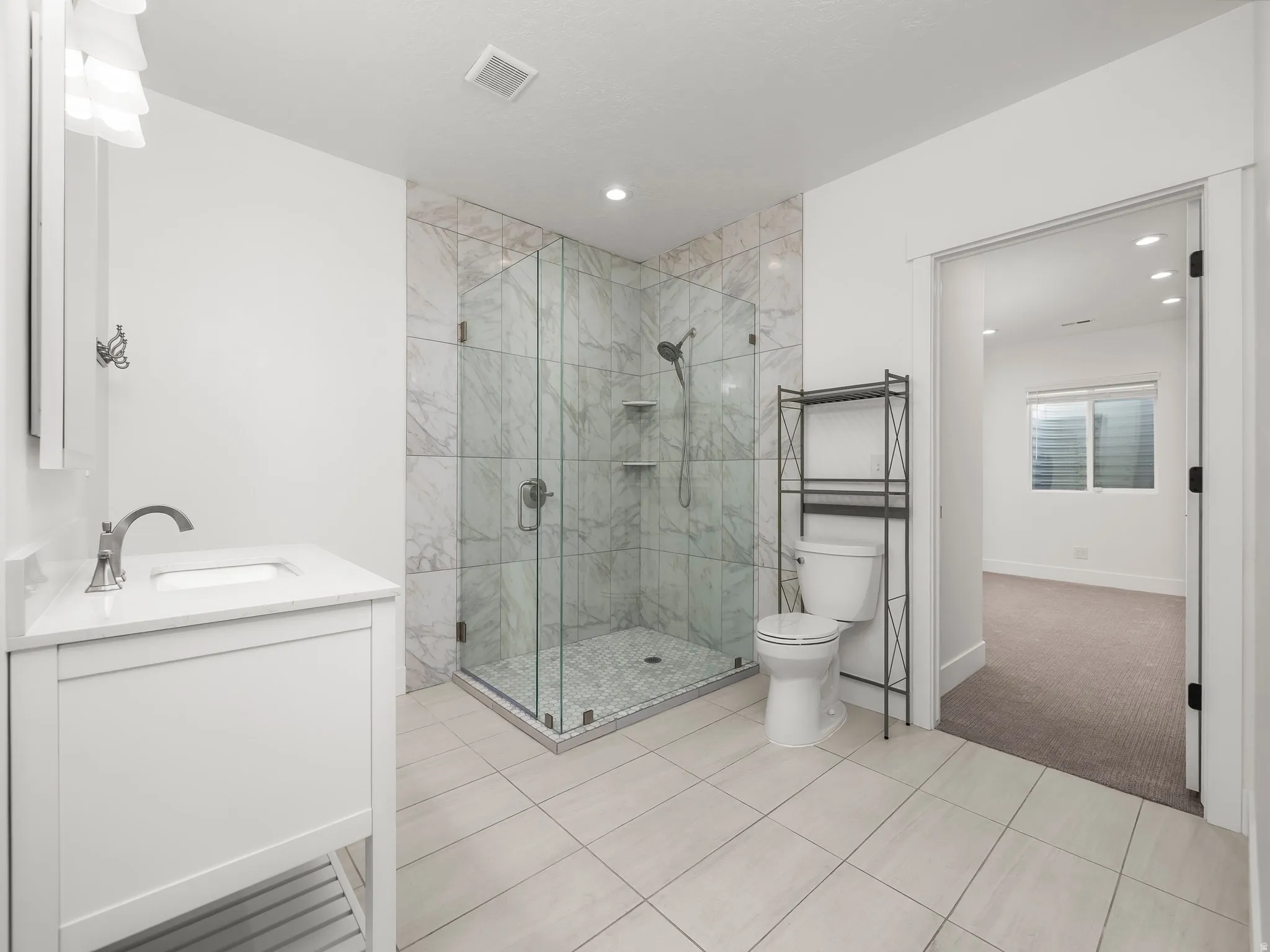 Full bathroom with vanity, a marble finish shower, light colored carpet, and light tile patterned floors