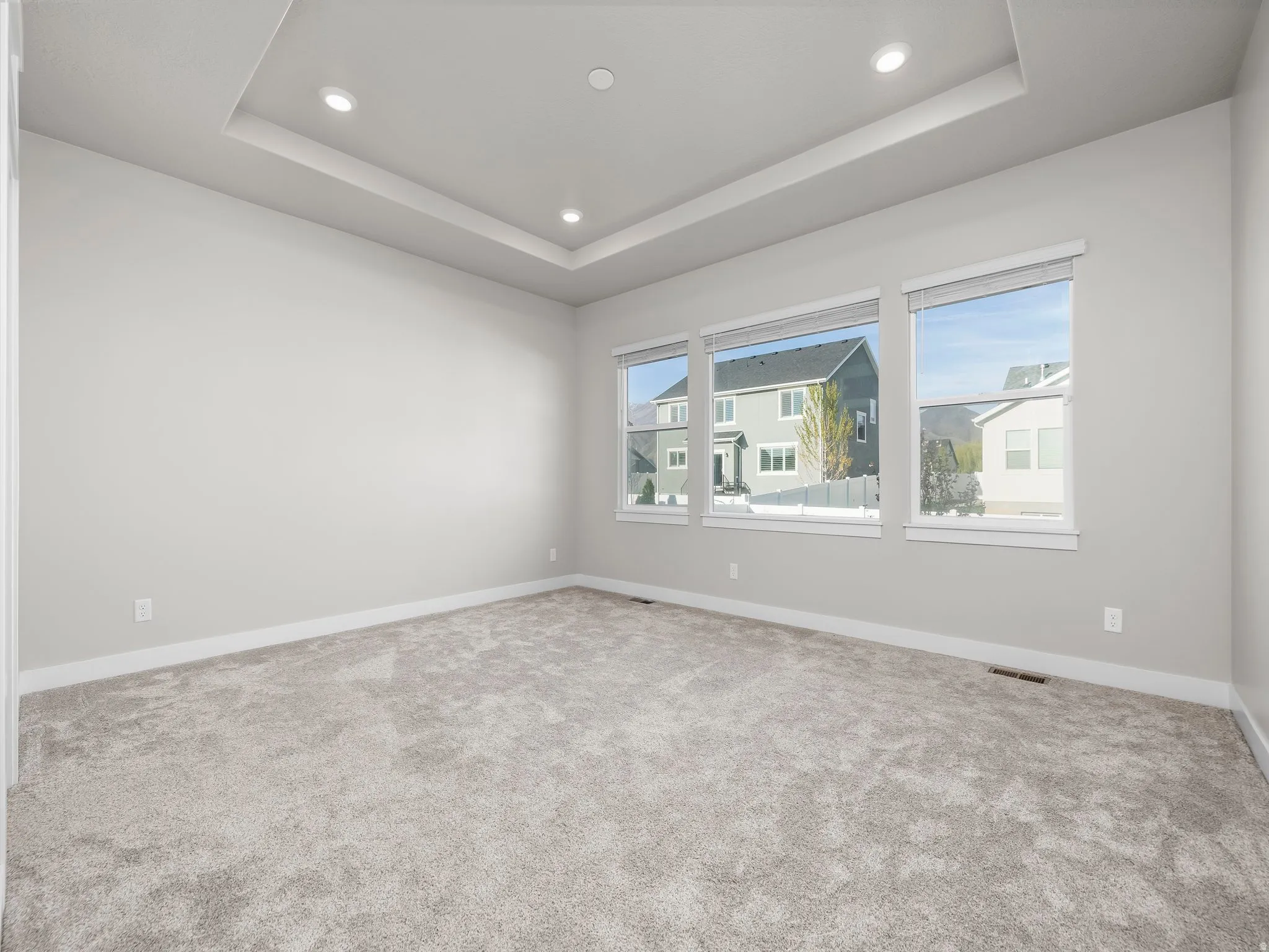 Carpeted empty room with recessed lighting and a tray ceiling