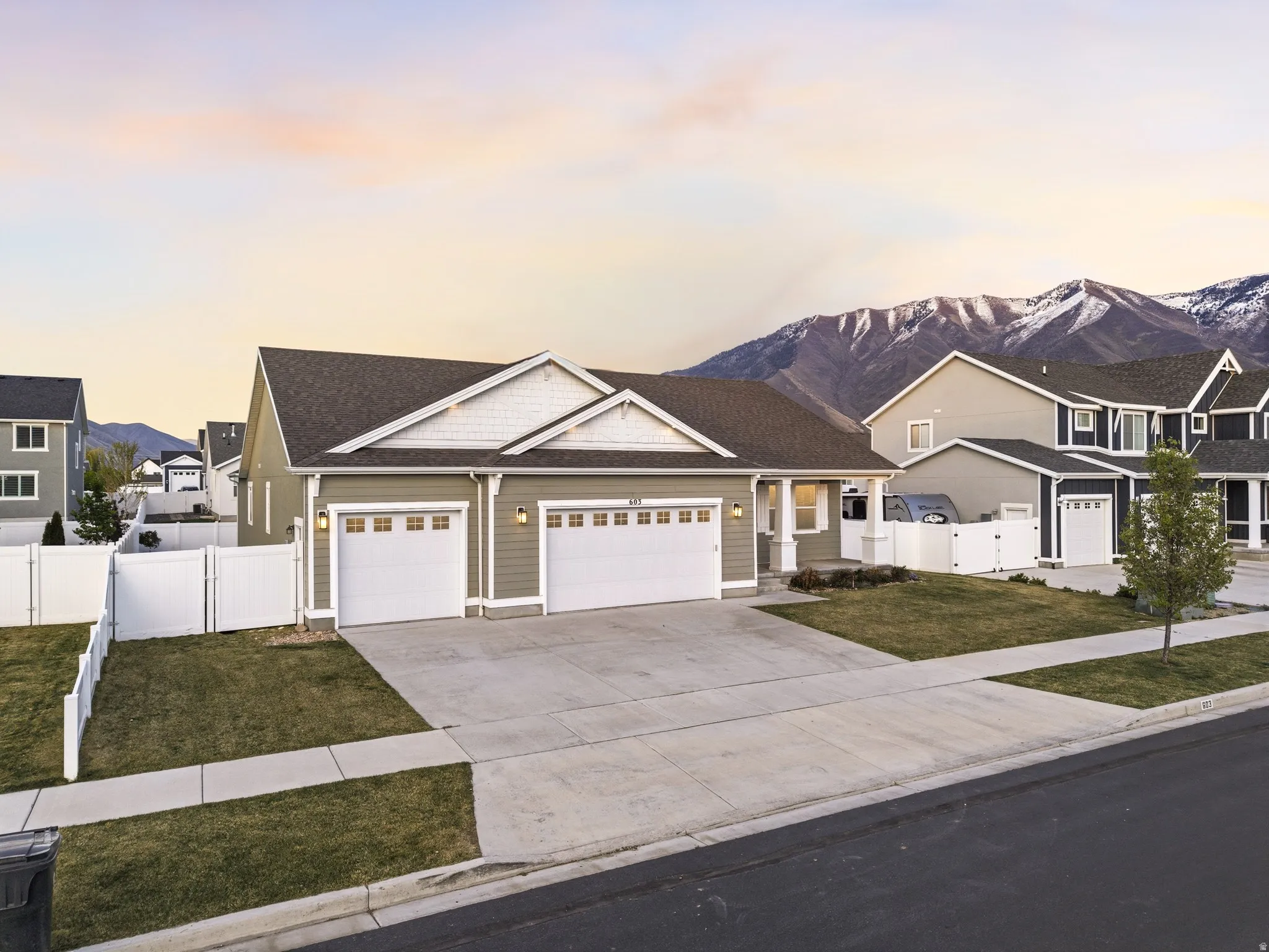 Craftsman-style house featuring an attached garage, concrete driveway, a mountain view, a gate, and a residential view