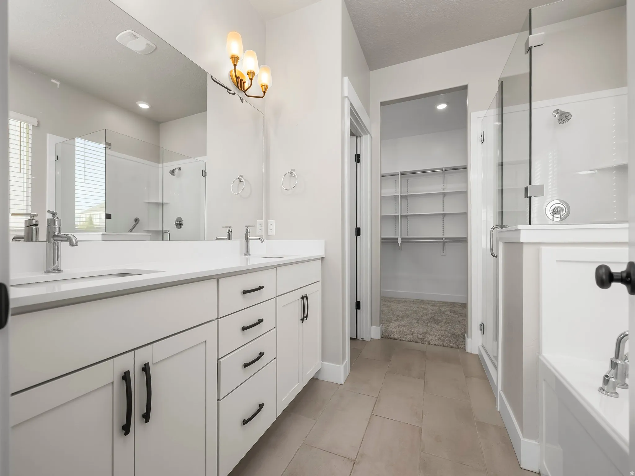 Full bath with a stall shower, double vanity, a walk in closet, and a bath