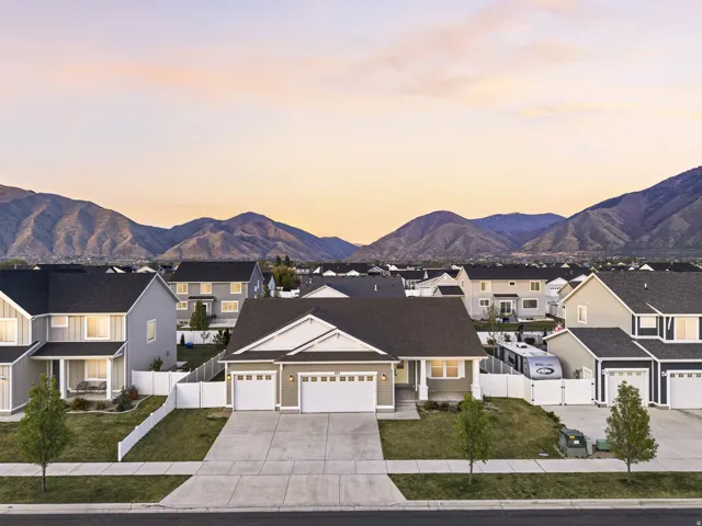 View of front of property with a garage, driveway, a residential view, a mountain view, and a gate