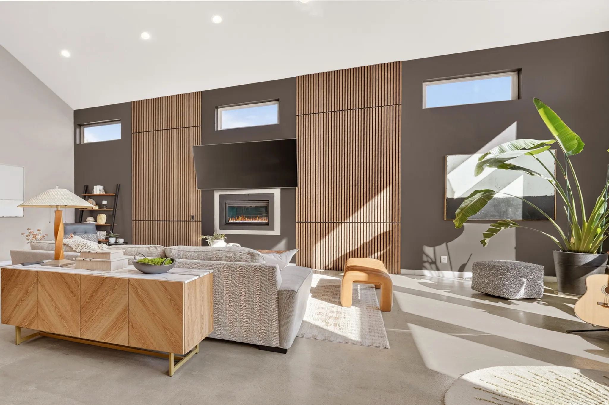 Living area with a glass covered fireplace, recessed lighting, concrete floors, healthy amount of natural light, and vaulted ceiling