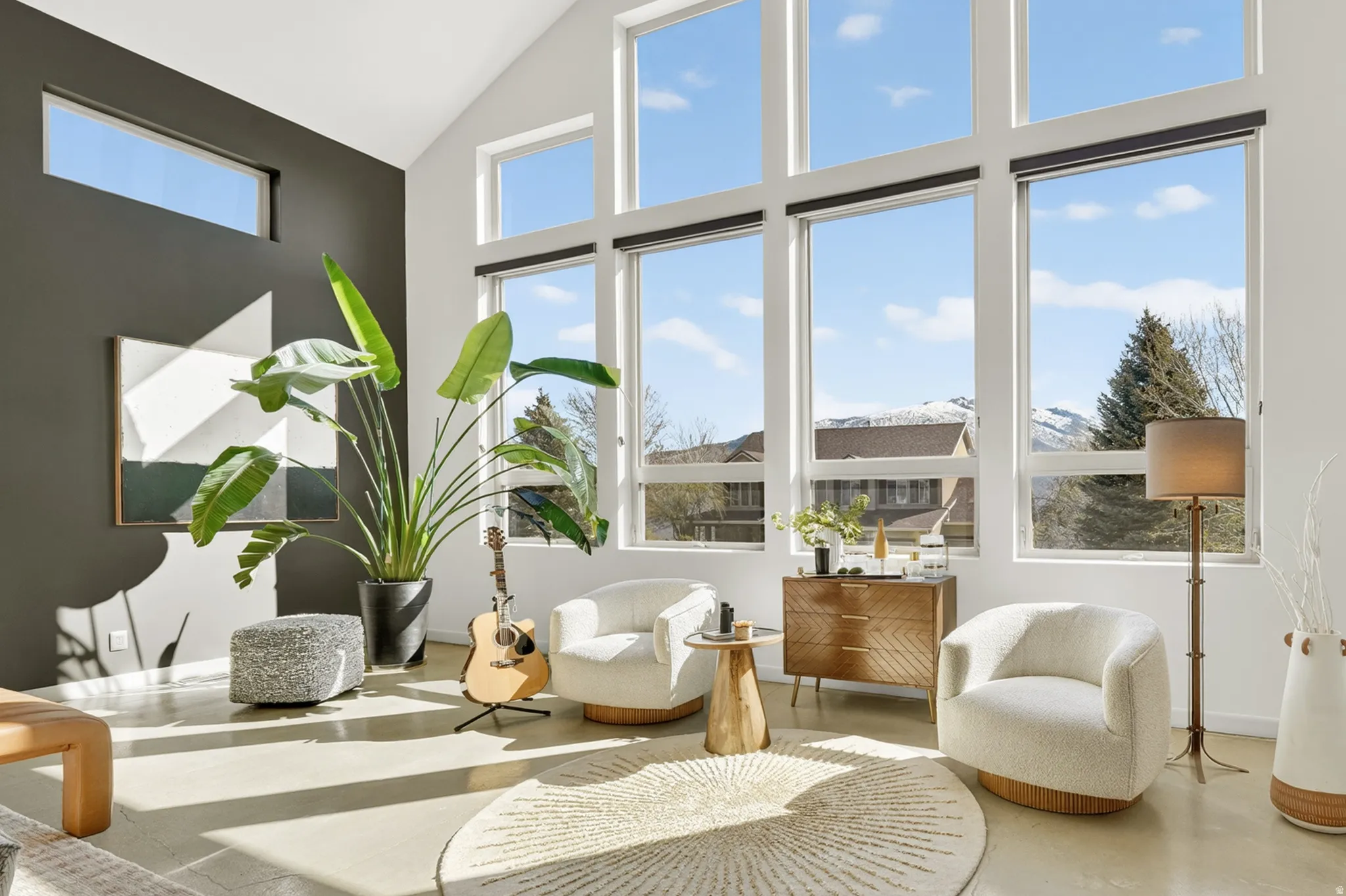 Living area with a glass covered fireplace, recessed lighting, concrete floors, healthy amount of natural light, and vaulted ceiling