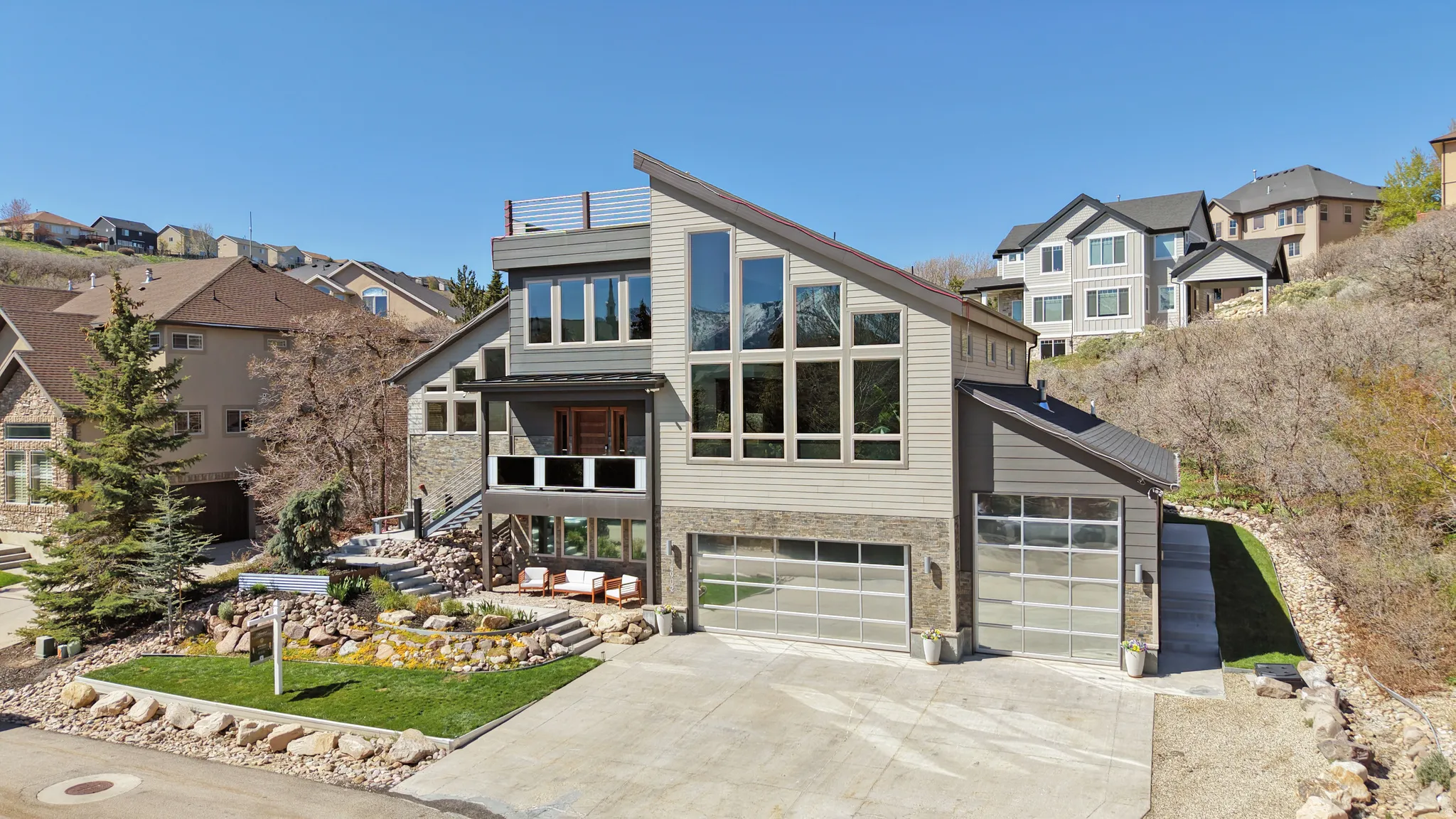 Contemporary home featuring stone siding, a residential view, driveway, and a garage