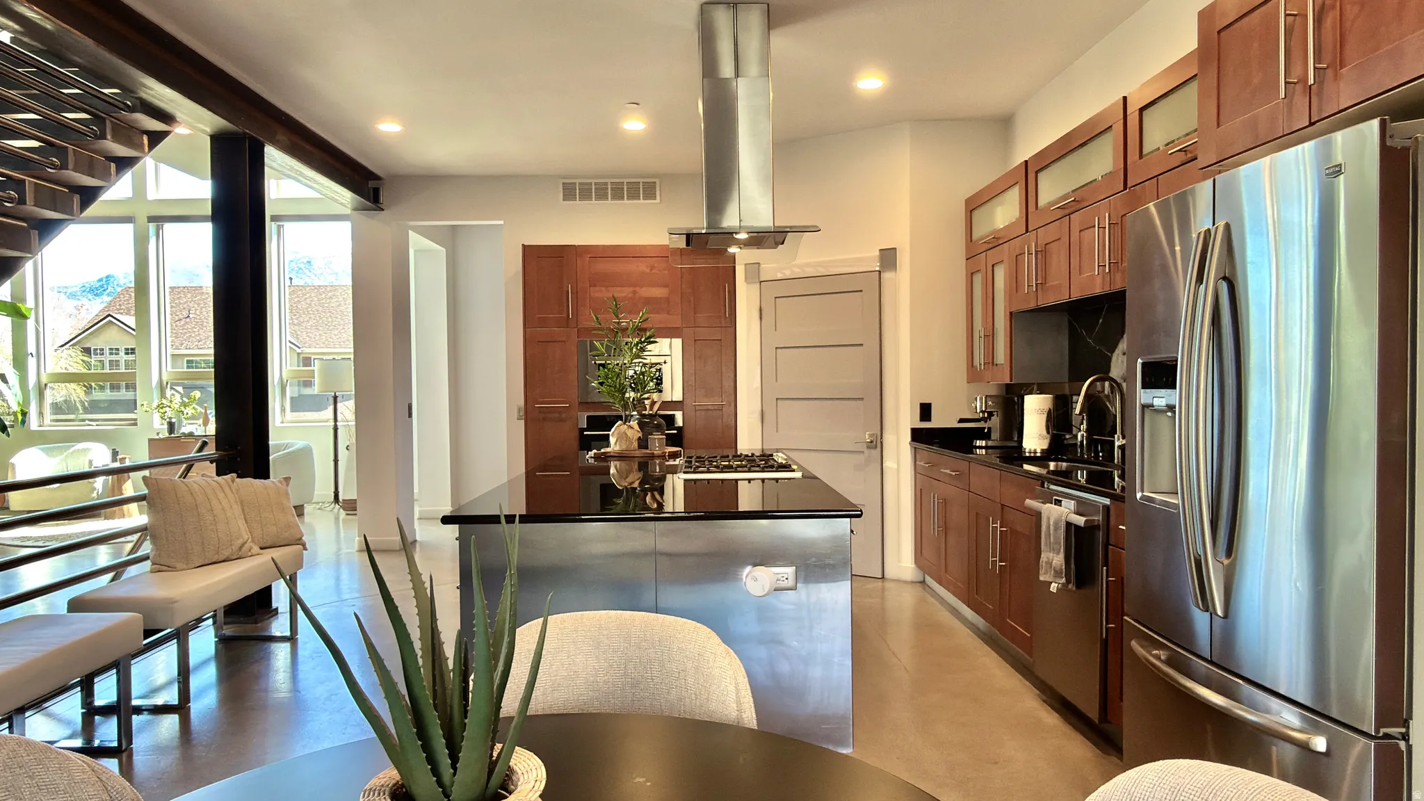 Kitchen with stainless steel appliances, glass fronted cabinets, a center island, island exhaust hood, and wood finish cabinetry