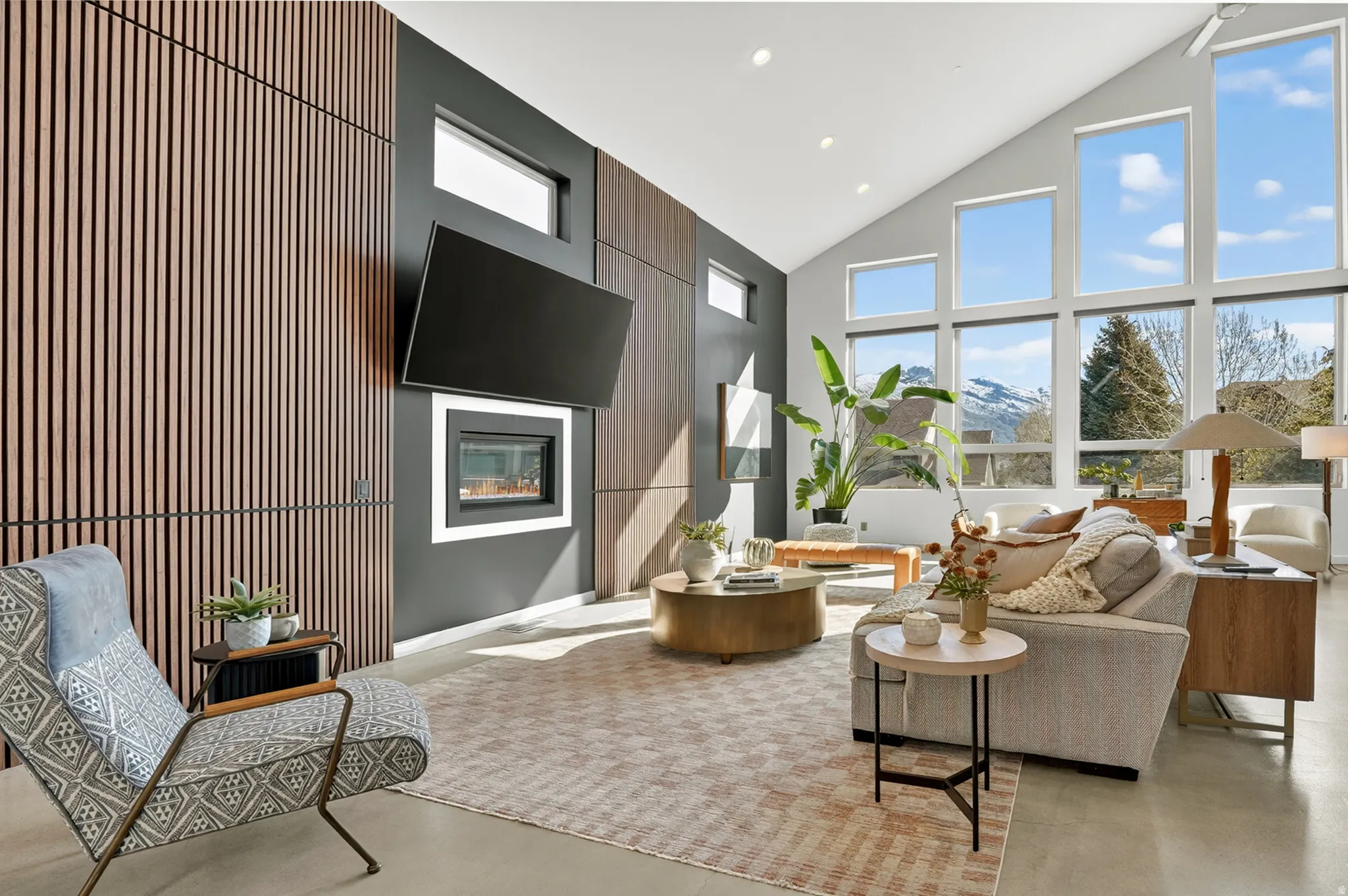 Living area with a glass covered fireplace, recessed lighting, concrete floors, healthy amount of natural light, and vaulted ceiling