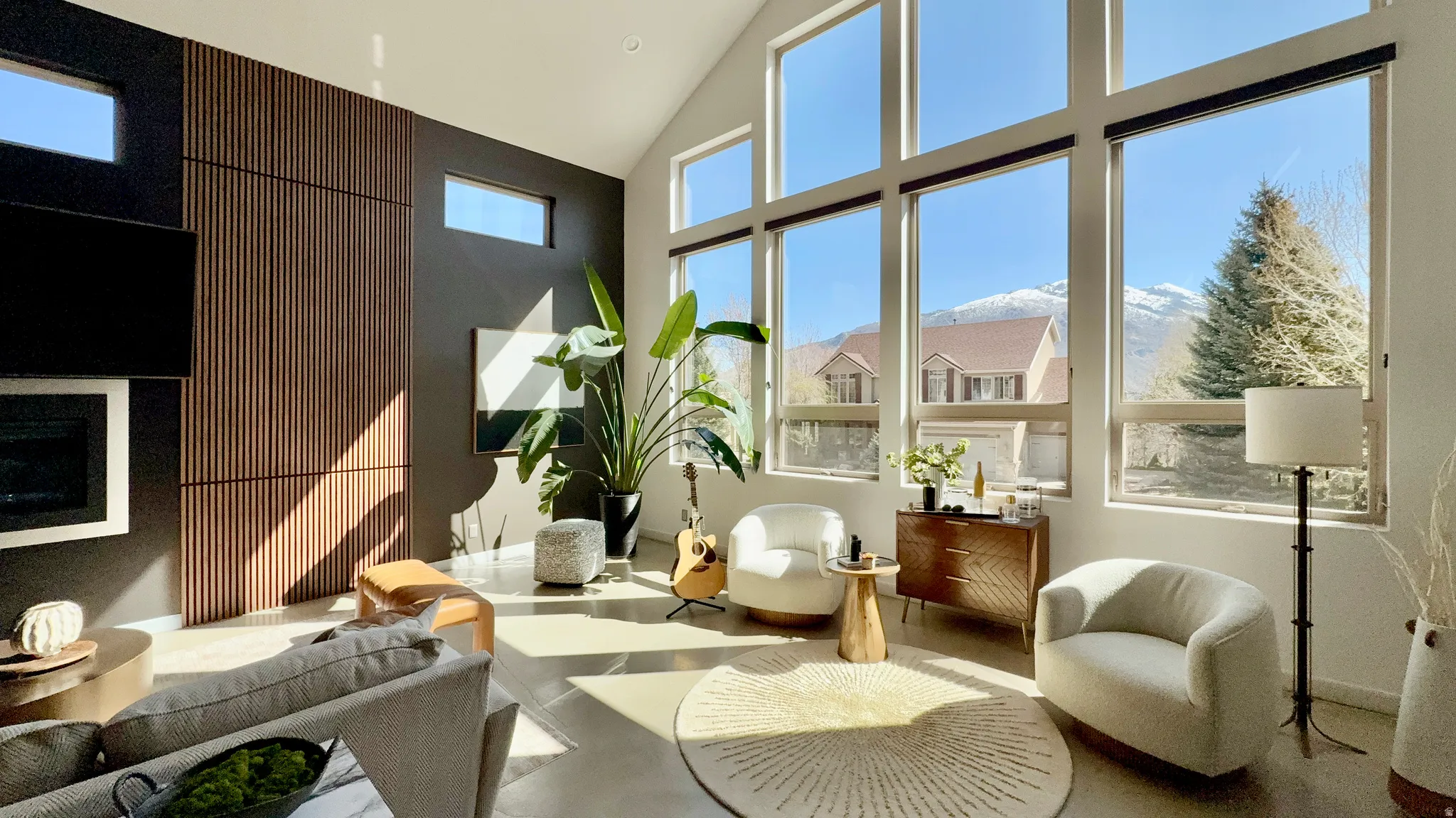 Living area with a glass covered fireplace, recessed lighting, concrete floors, healthy amount of natural light, and vaulted ceiling