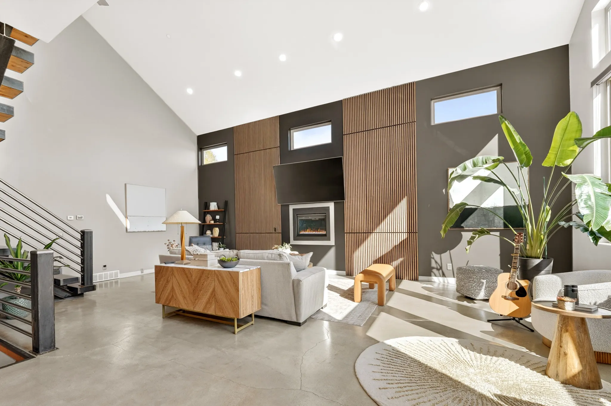 Living area with a glass covered fireplace, recessed lighting, concrete floors, healthy amount of natural light, and vaulted ceiling