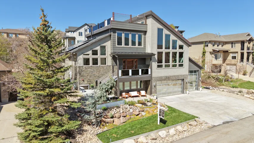 Contemporary house with stone siding, concrete driveway, a garage, and a residential view