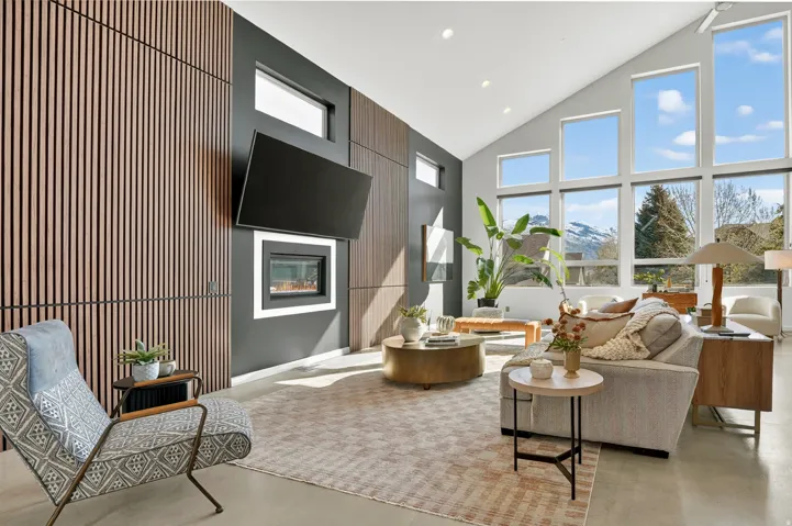 Living area with a glass covered fireplace, recessed lighting, concrete floors, healthy amount of natural light, and vaulted ceiling
