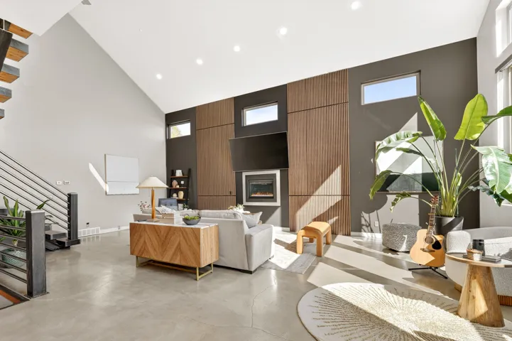 Living area with a glass covered fireplace, recessed lighting, concrete floors, healthy amount of natural light, and vaulted ceiling