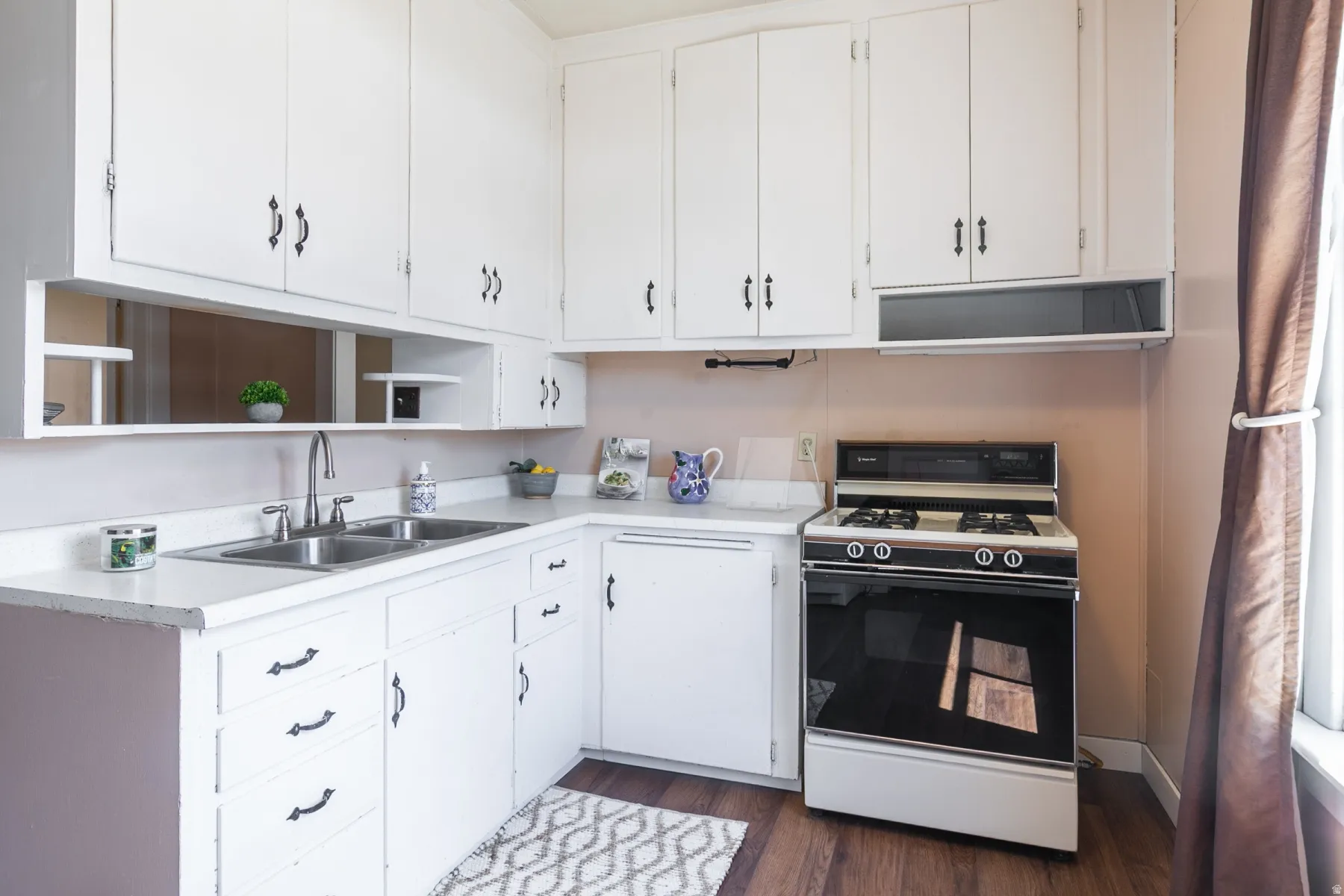 Kitchen featuring range with gas cooktop, light countertops, white cabinets, and dark wood-style floors