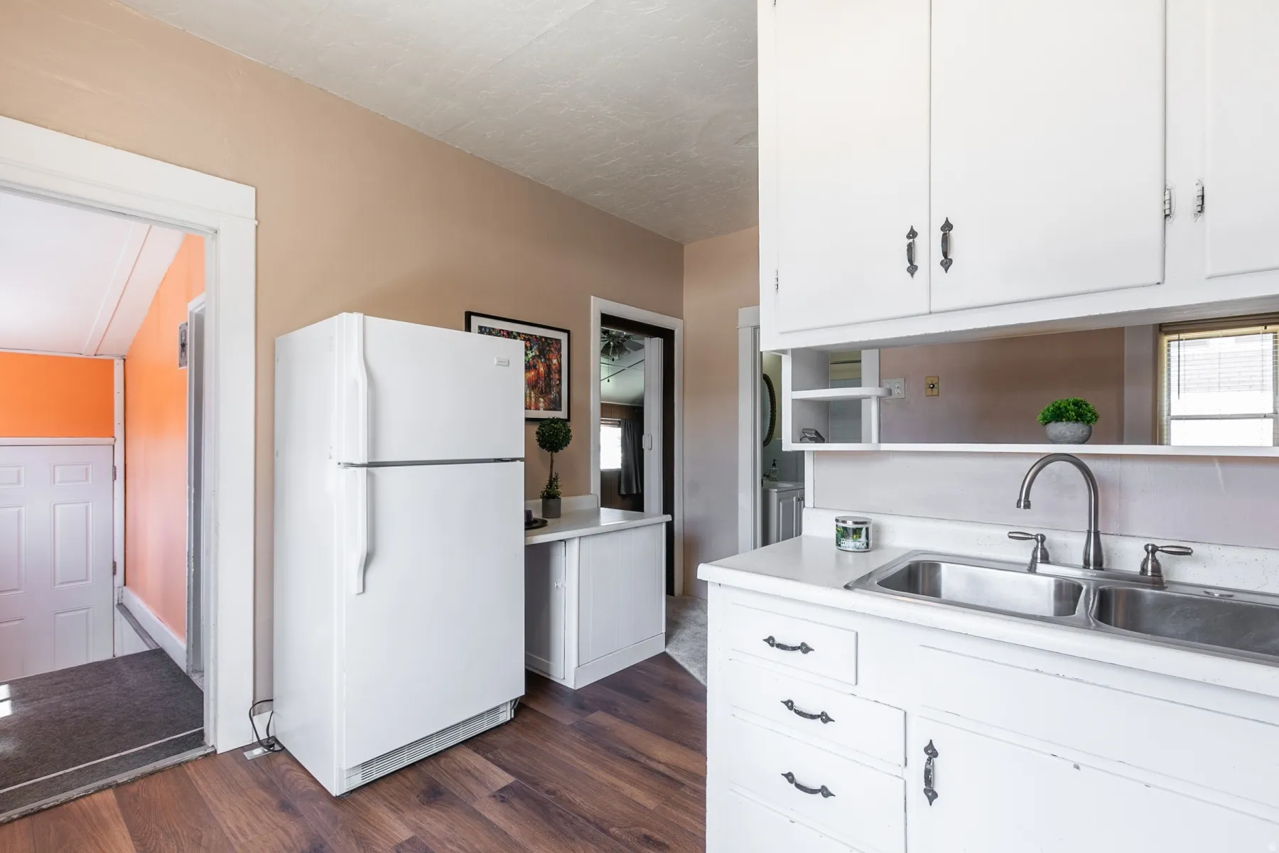 Kitchen with freestanding refrigerator, light countertops, white cabinets, dark wood-type flooring, and open shelves