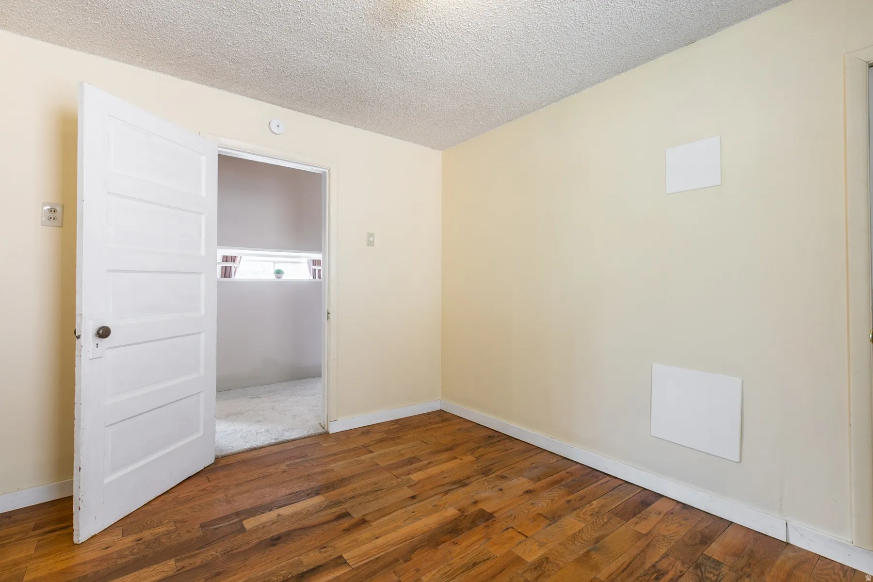 Empty room with hardwood / wood-style floors and a textured ceiling