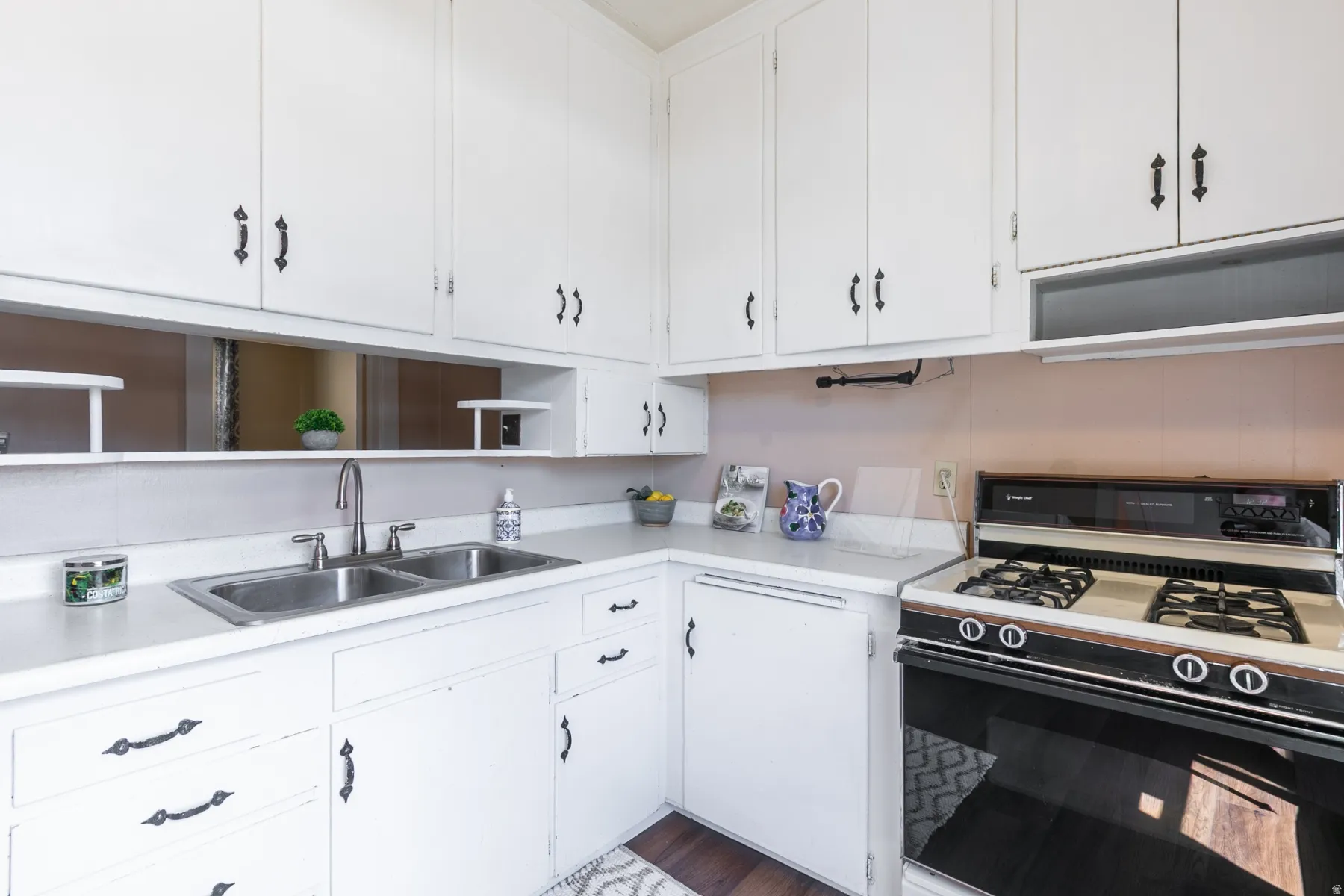 Kitchen featuring gas stove, white cabinetry, light countertops, and dark wood-type flooring