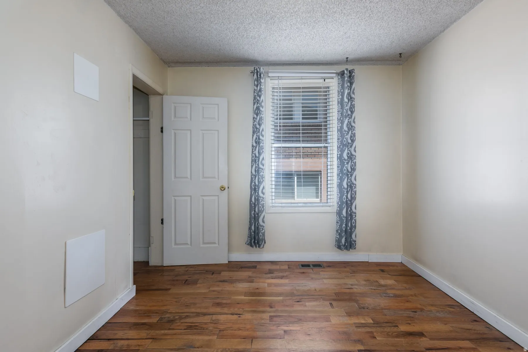 Unfurnished bedroom with dark wood finished floors and a textured ceiling