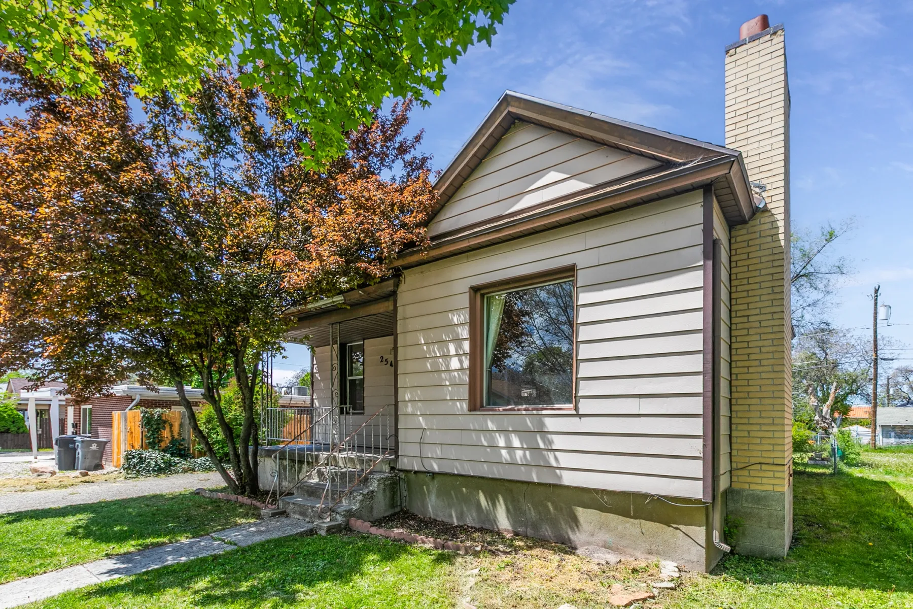 View of front of property with a front yard, a chimney, and covered porch