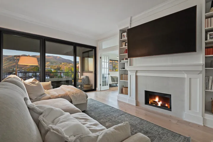 Living room featuring light wood-style floors, ornamental molding, a tile fireplace, and built in features