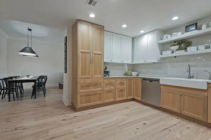 Kitchen with light wood-type flooring, tasteful backsplash, open shelves, dishwasher, and ornamental molding