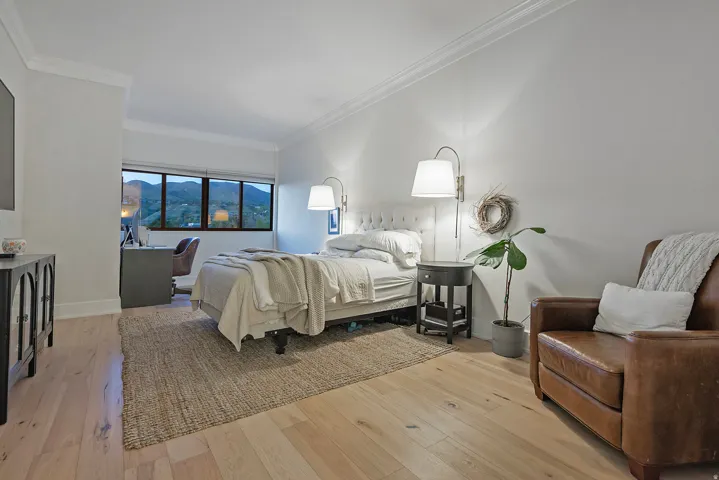 Bedroom featuring light wood-style flooring, crown molding, and a mountain view