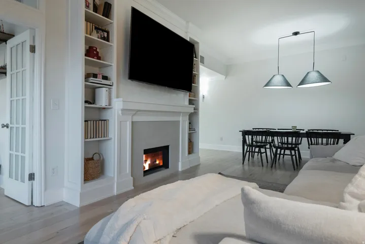 Living area with light wood finished floors, ornamental molding, a tile fireplace, and built in shelves