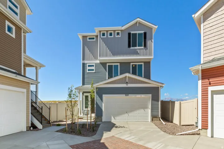 View of front facade with driveway, board and batten siding, and a gate