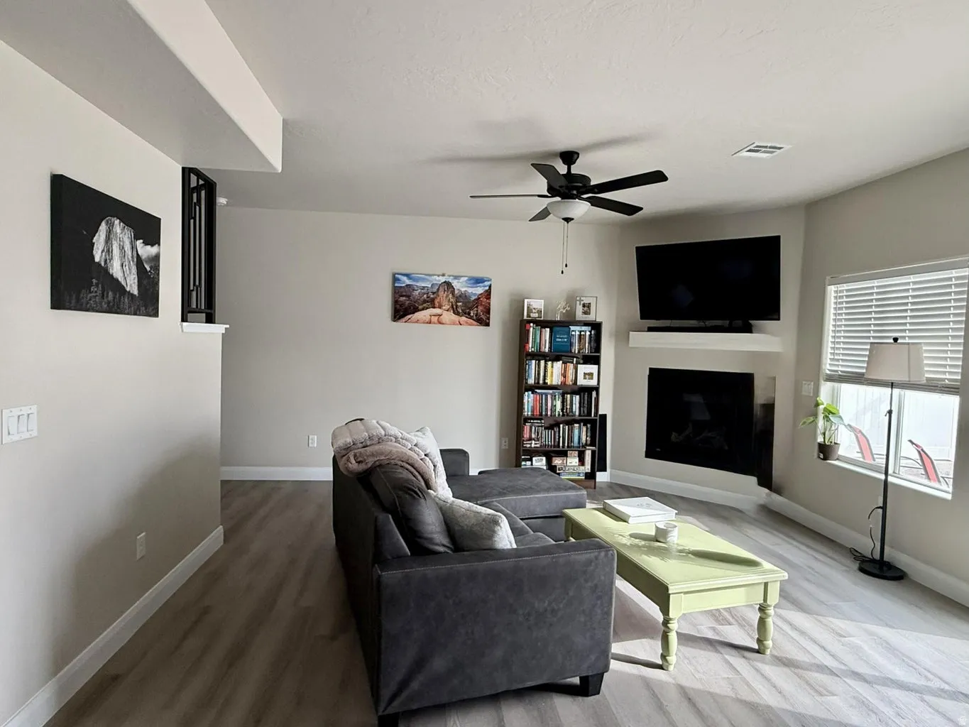 Living area with light wood-style floors, a ceiling fan, and a fireplace