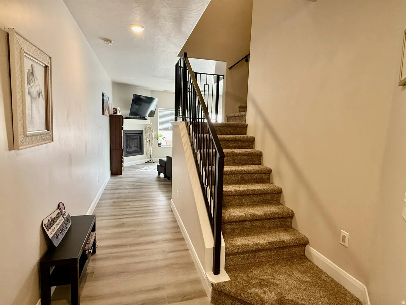 Staircase featuring a glass covered fireplace and wood finished floors