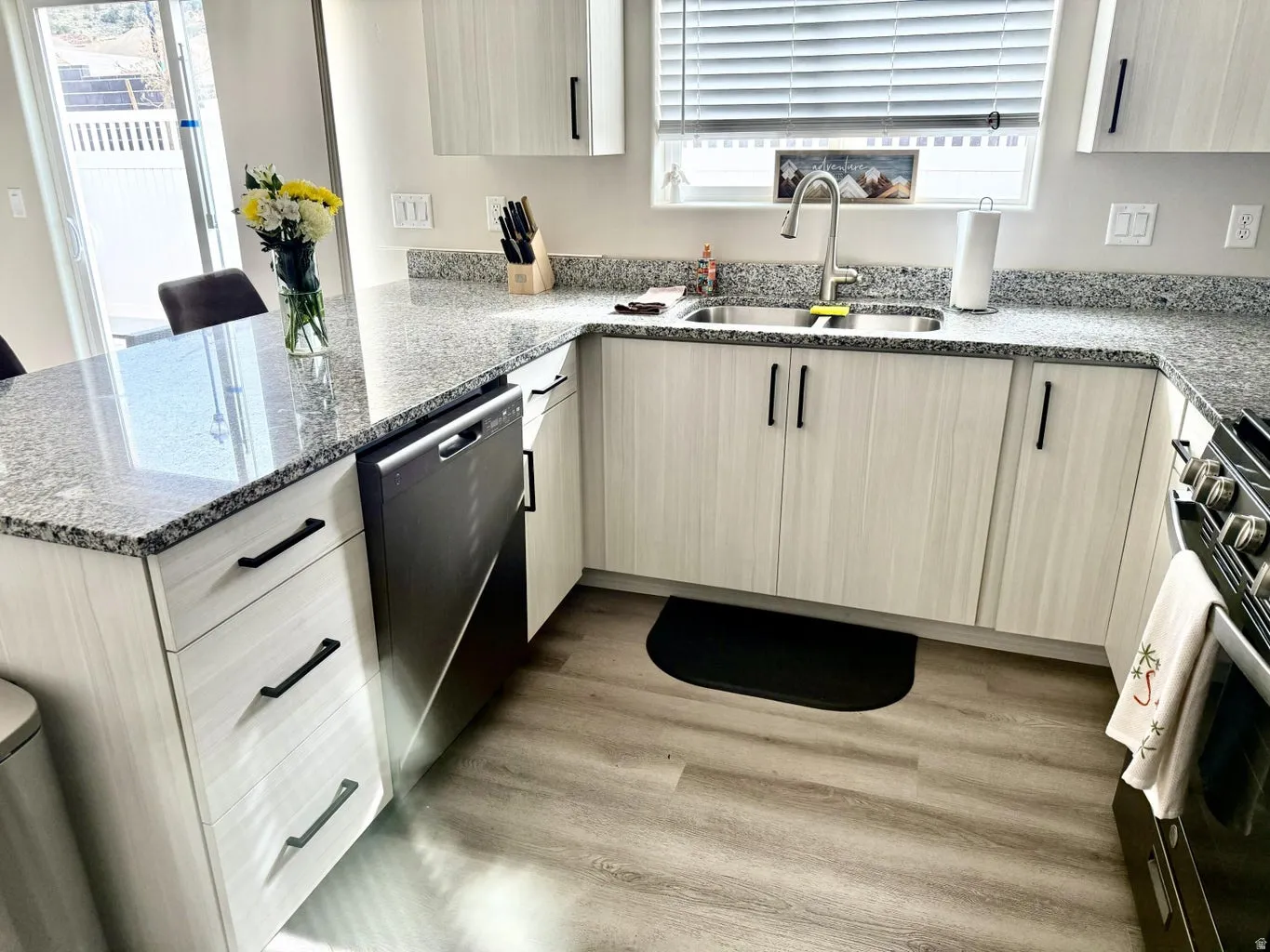 Kitchen with dark stone countertops, a peninsula, stainless steel appliances, and light wood finished floors