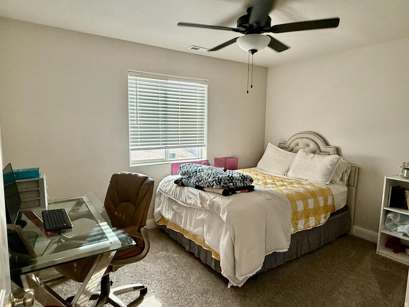 Carpeted bedroom featuring an office area and a ceiling fan