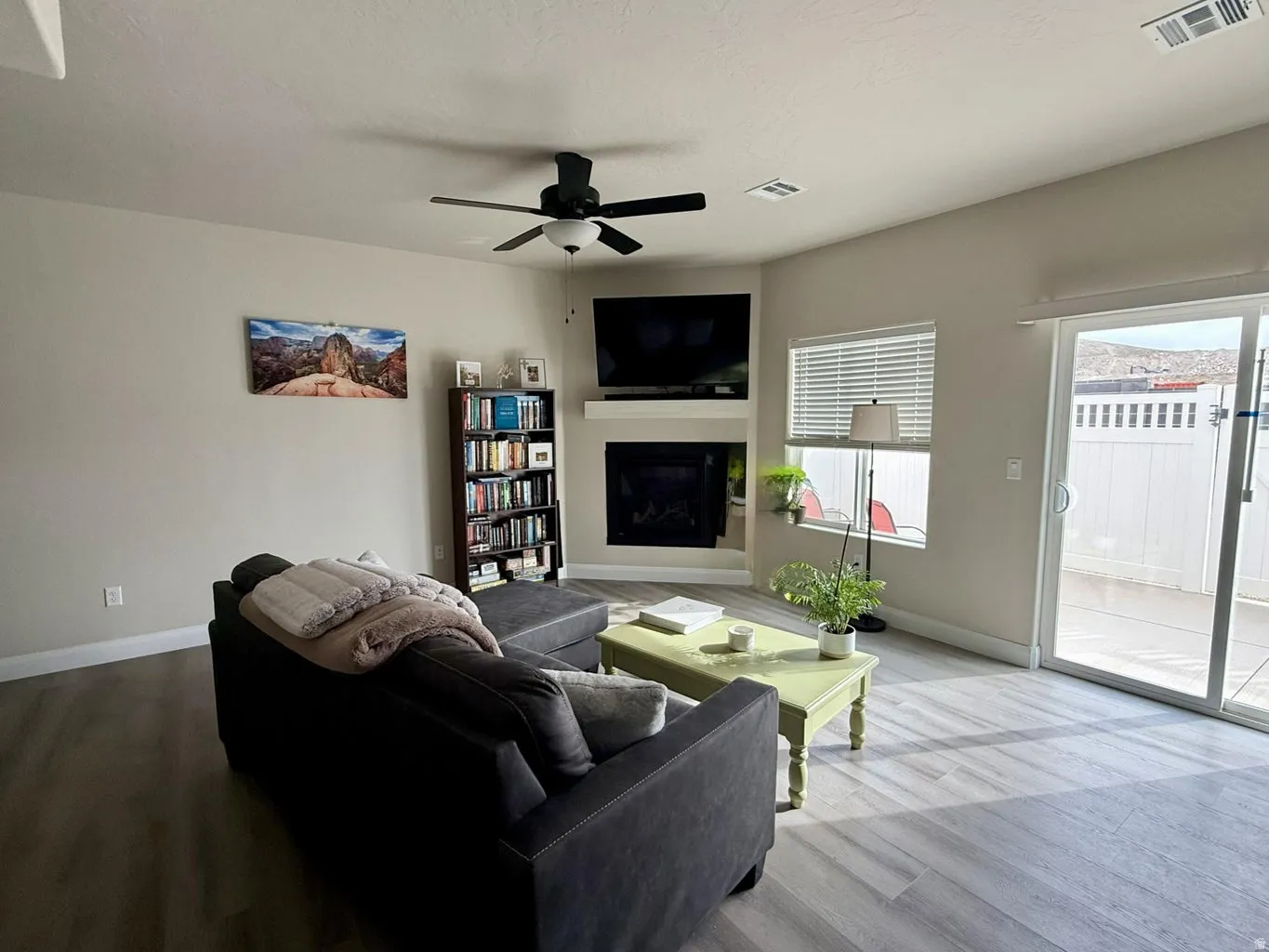 Living area with wood finished floors, a fireplace, and a ceiling fan