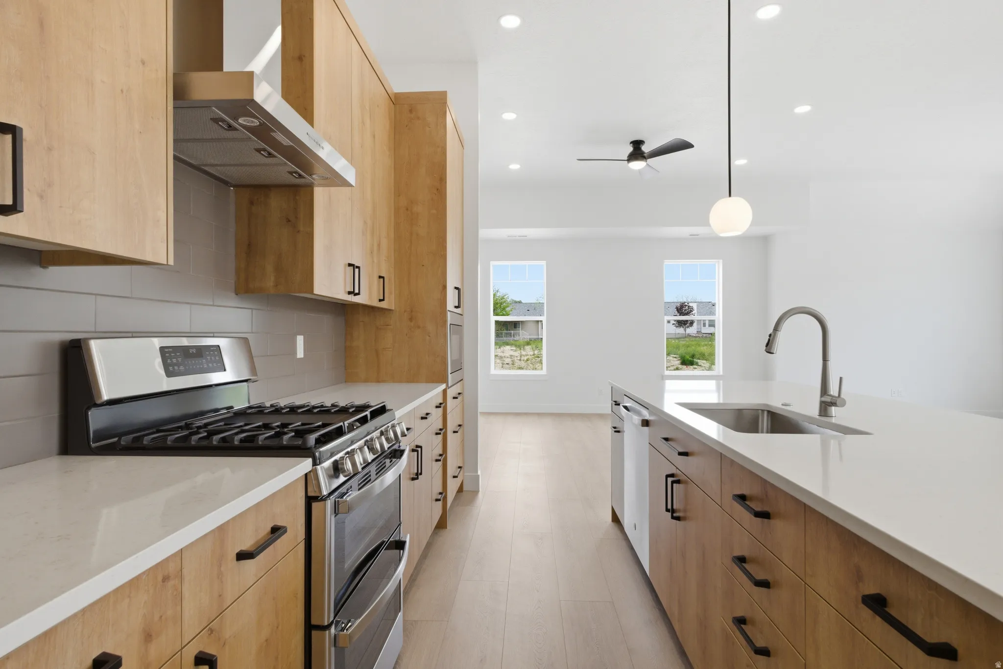 Kitchen featuring range with two ovens, two tone color scheme, light stone counters, tasteful backsplash, and hanging light fixtures