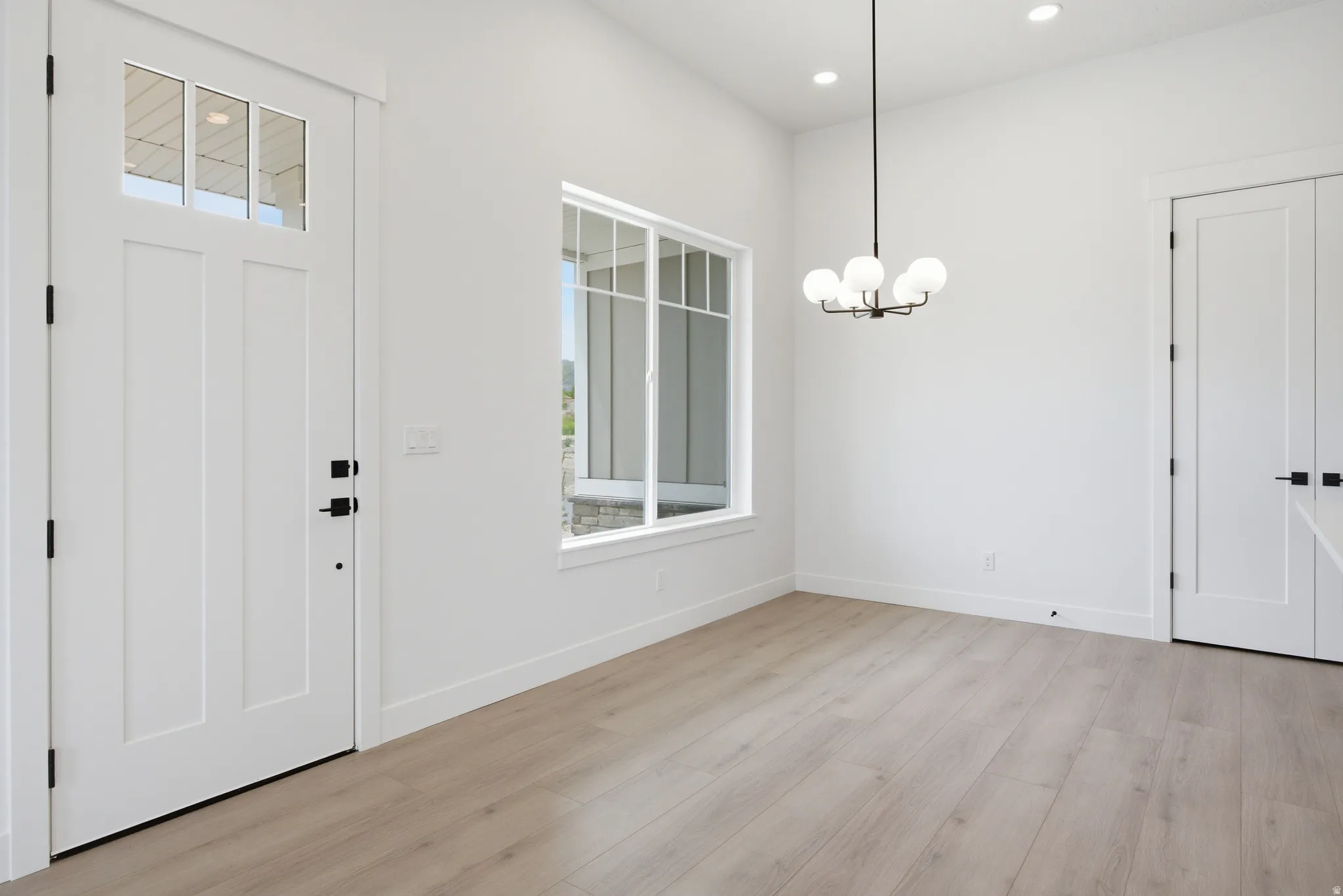 Foyer with light wood-type flooring and hanging lights
