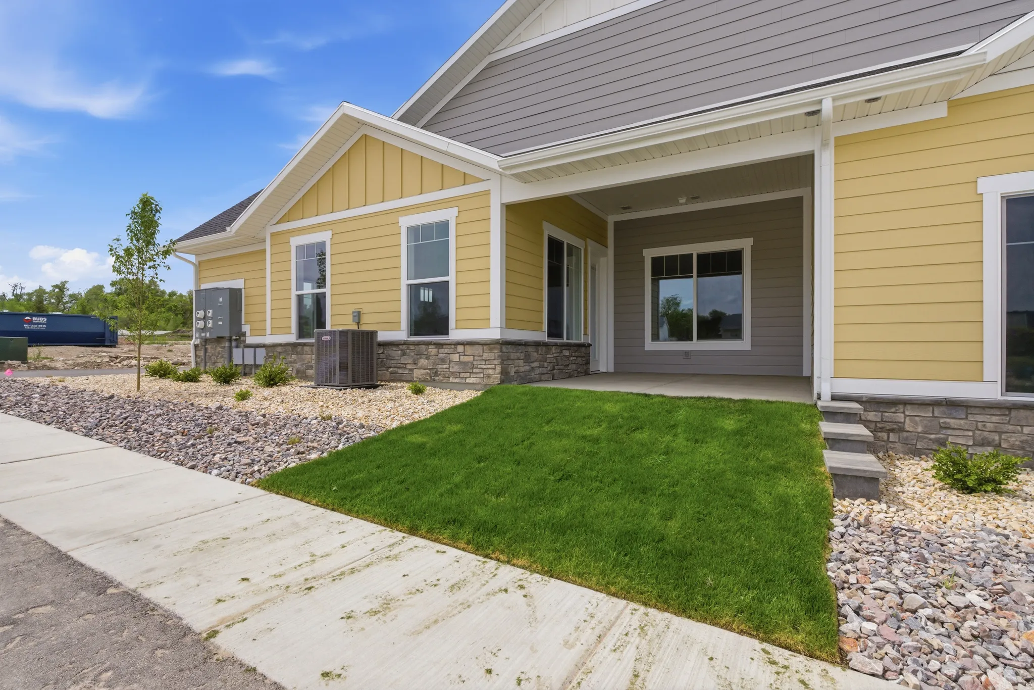 Property entrance with stone siding, a porch, board and batten siding, and a yard